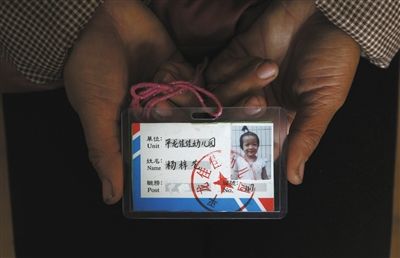 3月23日，云南省丘北县平龙村，杨梓艺的母亲拿着女儿生前幼儿园的胸卡。